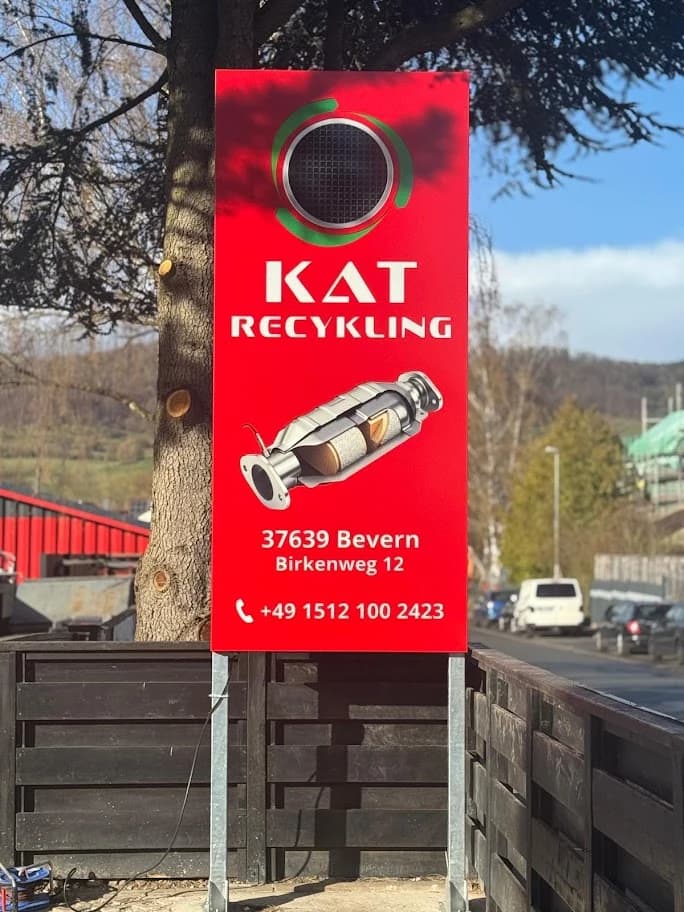 Czerwony pionowy szyld KAT Recycling z grafiką katalizatora i adresem w Bevern